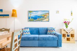 een blauwe bank in een woonkamer met een schilderij aan de muur bij Chiara & Giulia Apartments by HDSalento in Leuca