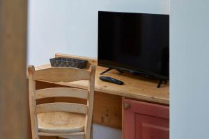 einen Holzschreibtisch mit einem TV und einem Stuhl in der Unterkunft Garnì San Giorgio Della Scala Rooms and Breakfast in Trient
