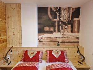 - une chambre avec deux oreillers rouges et une photo d'une machine à coudre dans l'établissement Ferienwohnung Schnalstal " Die Schneiderei ", à Senales
