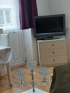 a living room with a tv on a dresser with chairs at Lux Apartment in Gatwick in Crawley