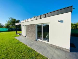 un bâtiment blanc avec des portes en verre sur une pelouse dans l'établissement Čarovný apartmán Bojnice a okolie, à Koš