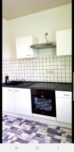 a kitchen with white cabinets and a black dishwasher at Ferienwohnung Hesse in Grimma