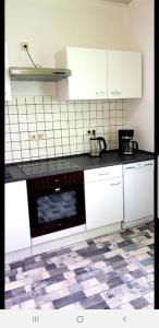 a kitchen with white cabinets and a black dishwasher at Ferienwohnung Hesse in Grimma