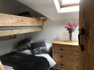 a bedroom with a bunk bed and a dresser with flowers at Primrose Cottage - Tideswell, Peak District in Tideswell