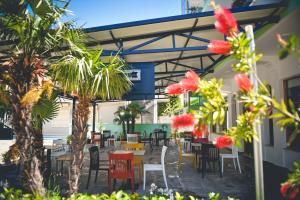 a patio with tables and chairs and palm trees at Sangiovanni in Shëngjin