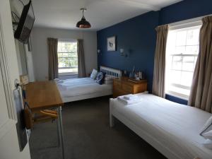 a bedroom with two beds and a desk and a table at The Sloop Inn in Kingsbridge