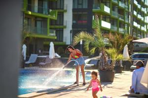 a woman and a child playing in a fountain at CRYSTAL ApartHotel & Spa Mamaia Nord in Mamaia Sat/Năvodari