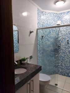uma casa de banho com um chuveiro, um lavatório e um WC. em Lindo apartamento com vista para o mar em Caraguá! em Caraguatatuba