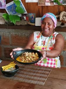 una donna che tiene una padella di cibo su un tavolo di Posada El Esfuerzo a Nuquí