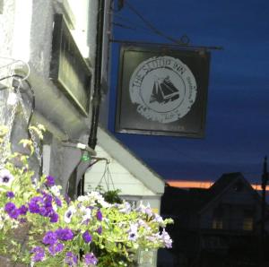 a sign on the side of a building with purple flowers at The Sloop Inn in Kingsbridge
