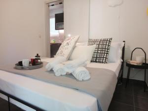 ein Bett mit weißen Kissen und ein Tablett mit Handtüchern in der Unterkunft My Sweet Home BnB North in Athen