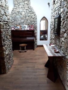 a room with a table and a piano in a stone wall at Room with a view in Killarney