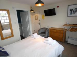 a bedroom with two beds and a chair and a mirror at The Sloop Inn in Kingsbridge