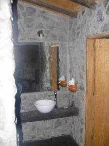 baño con lavabo y pared de piedra en Portal Del Tala Centro Ecoturístico en Alpa Corral