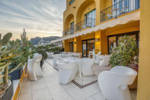 a patio with white chairs and plants on a building at Hotel Albatros Varigotti in Varigotti