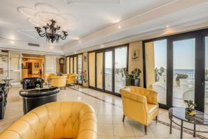 a living room with yellow furniture and large windows at Hotel Albatros Varigotti in Varigotti