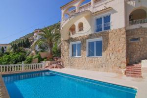 eine Villa mit einem Pool vor einem Haus in der Unterkunft Villa con piscina y vistas al mar - Mar 27 H in Calpe