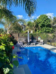 a swimming pool with two chairs and a fountain at Private Papamoa Beach Paradise in Papamoa