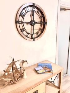 a clock hanging on a wall above a wooden table at NICOL APARTMENS in Preveza