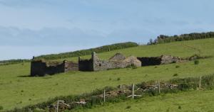 an old stone building on a hill in a field at The Sloop Inn in Kingsbridge