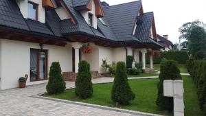 a house with a black roof and a green yard at Witowiański Dworek in Witów