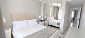 una camera bianca con letto e specchio di Quiet 2 bedroom apartment-Sleeps up to 6 a Mijas