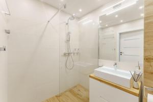 a white bathroom with a shower and a sink at SUN 7 - osiedle JANTAR in Kołobrzeg
