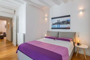 Un dormitorio blanco con una cama grande con almohadas moradas en Castaldi 18 - Milano in tasca en Milán