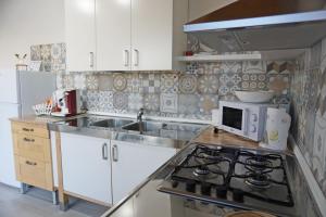 una cucina con lavandino e piano cottura forno superiore di Holiday House Villa AleGiù Marzamemi a Reitani