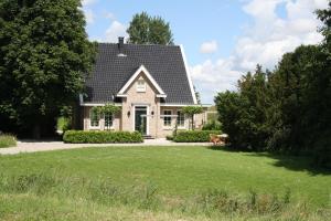 une maison avec un chien assis dans une cour dans l'établissement Studio Bed and Breakfast Zaans Moment, à Assendelft