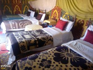 a room with three beds with colorful blankets at Bivouac ZAGORA in Zagora
