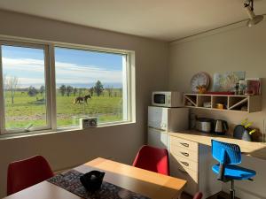 a kitchen with a table and a horse outside the window at Bakland ad Lágafelli Apartment in Búðarhólshverfi
