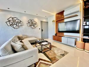 sala de estar con sofá blanco y TV de pantalla plana en New Modern Lux City Condo With Pool And Gym Ocean View Santo Domingo, en Ciudad Nueva