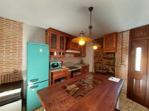 La cuisine est équipée d'une table en bois et d'un réfrigérateur bleu. dans l'établissement Casa Honorio, à Santa Marina del Sil