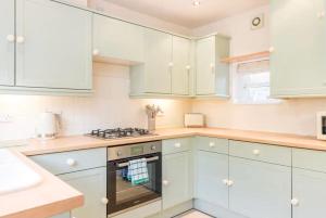 cocina blanca con armarios blancos y horno en Stunning 2 bed Cottage in Saddleworth, en Dobcross