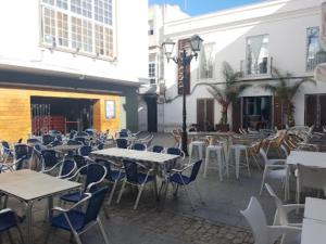 patio ze stołami, krzesłami, stołami i budynkami w obiekcie Apartamentos San Hiscio w mieście Tarifa