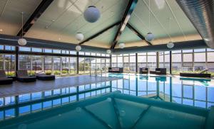 a large swimming pool in a building with windows at Rydges Horizons Snowy Mountains in Jindabyne