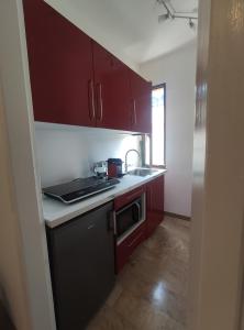 a small kitchen with red cabinets and a sink at Andaleppo in Mestre
