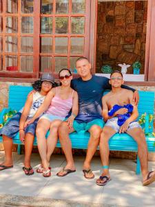 grupa ludzi siedzących na niebieskiej ławce w obiekcie Varandas do Arraial- Hostel w mieście Arraial do Cabo