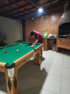 a man playing billiard in a room with a pool table at Varandas do Arraial- Hostel in Arraial do Cabo
