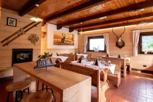 a restaurant with wooden tables and chairs and a fireplace at Baita da Rico Zoncolan in Sùtrio