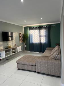 ein Wohnzimmer mit einem Sofa und einem Flachbild-TV in der Unterkunft Home@Amalia’s in Rundu