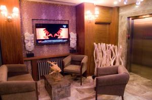 a waiting room with a fireplace and chairs and a tv at Kerimbey Hotel in Gemlik