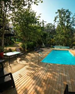 a swimming pool on a wooden deck with a table and chairs at Cabanas de Udra in Pontevedra