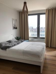 a white bed in a bedroom with a large window at UniQue 106 in Gdynia