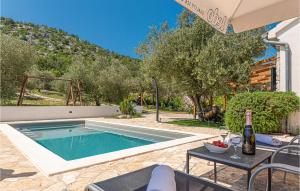 a villa with a pool and a table with a bottle of wine at Stunning Home In Vodice With 2 Bedrooms, Wifi And Outdoor Swimming Pool in Vodice