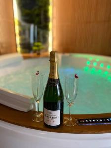 butelkę wina i dwa kieliszki wina obok wanny w obiekcie Esprit BALI ....LOVE SPA, Sauna de luxe à Mulhouse w Miluzie