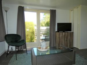 a living room with a table and a chair and a television at Chalet nr 10 op Bospark Trimunt in Marum