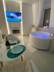 a white bathroom with a tub and a table with glasses at Esprit MALDIVES ...... SPA LOVE au coeur de Mulhouse in Mulhouse