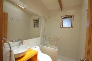 uma casa de banho branca com um lavatório e um WC em Cabañas en la naturaleza a pasos de la Playa em La Serena